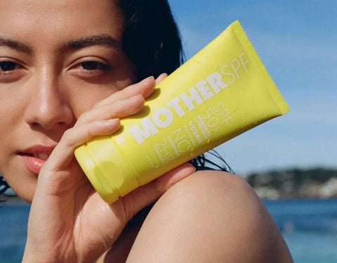 Model holding yellow Mother SPF Natural Physical Sunscreen SPF50