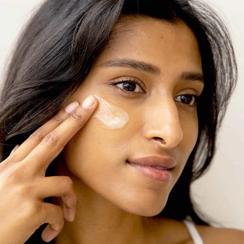 Woman applying cleansing balm to her cheek.