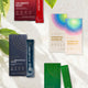 Various health and wellness products including 'Calibrate Reds', 'Essential Rainbow', and 'Tabolism Plus Coffee' on a light background with green leaves.