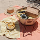 Beach setup with a woven basket, camera, lemons,a hat on a towel and a Nourished Life Beauty Box