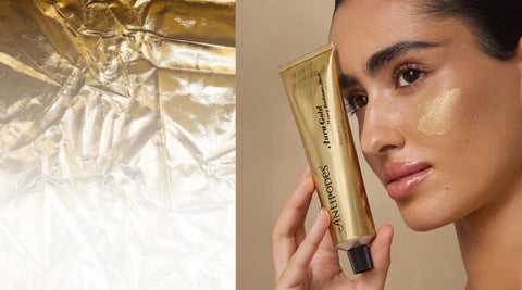 Woman holding a gold cosmetic tube with close-up of gold crystals on a beige background