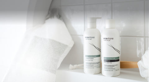 Two bottles of Ecostore shampoo and conditioner on a bathroom shelf with a towel in the background.