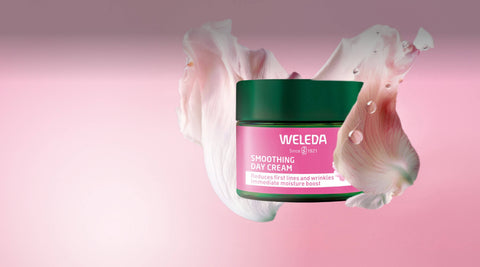 Weleda cream jar with pink flowers on a pink background.