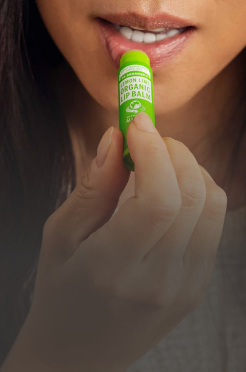 Person holding a green organic lip balm close to their mouth