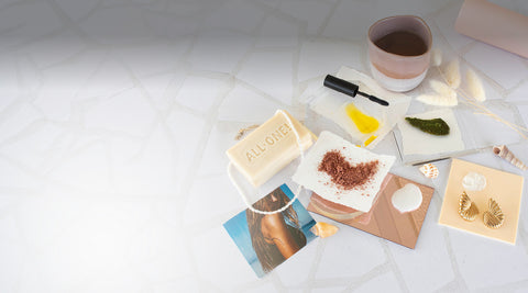 Collection of beauty products including a bar of soap, a small bowl, and a cosmetic brush on a white surface.