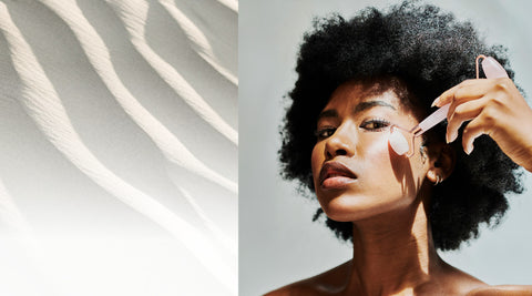 Woman applying makeup with a brush on a neutral background