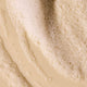 Close up of bubbly shampoo swatch on a beige background.