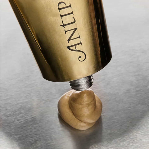 Gold tube of Antipodes aura gold being squeezed out on a grey surface