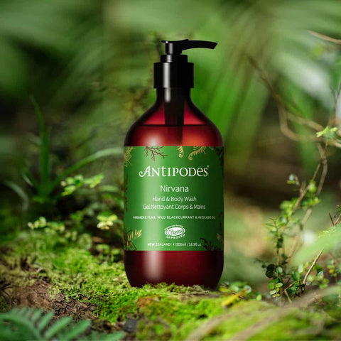 Antipodes Nirvana Hand & Body Wash bottle in a natural setting with greenery.