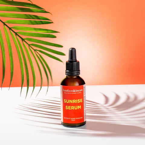 Bottle of 'Sunrise Serum' with a palm leaf on an orange background