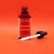 Bottle of 'Sunrise Serum' with dropper on an orange background