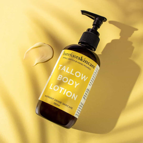 Bottle of tallow body lotion with a pump on a yellow background with a swatch of lotion.