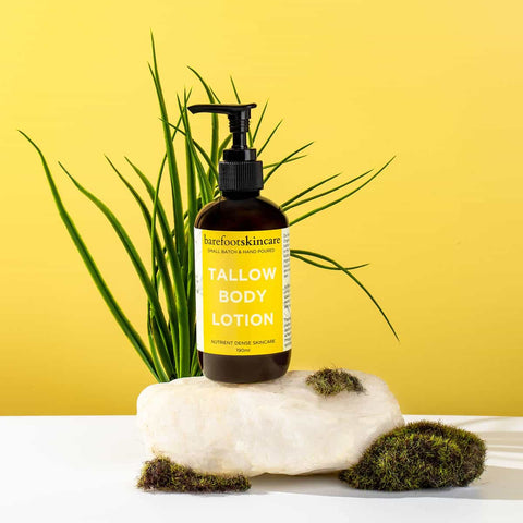 Bottle of tallow body lotion on a white surface with a yellow background