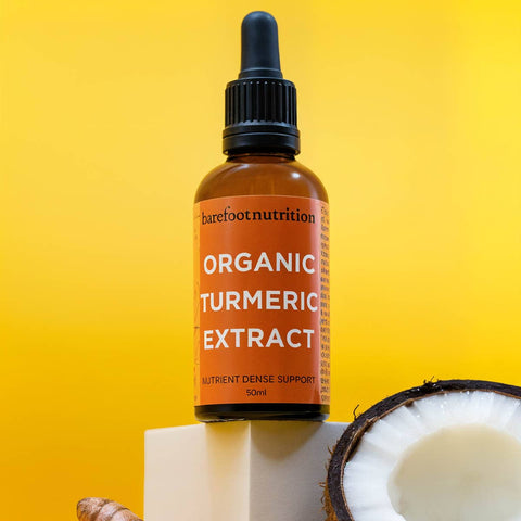 Bottle of organic turmeric extract on a yellow background with fresh turmeric and coconut. 