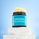 Barefoot Skincare Unscented Tallow Balm jar on a marble block with a blue background, showing texture of product.