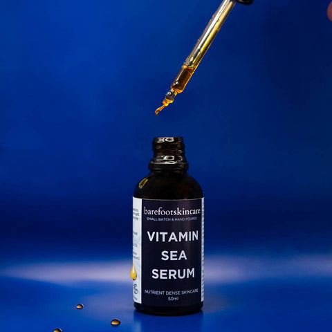 Bottle of Vitamin Sea Serum with a dropper on a blue background