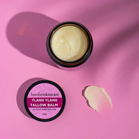 Ylang Ylang Tallow Balm jar with lid on a pink background with a swatch shown.