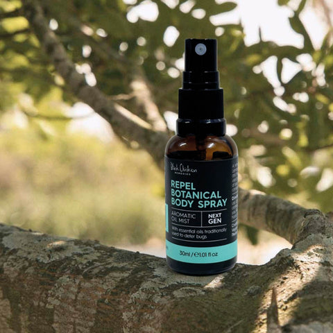 Repel Botanical Body Spray bottle on a tree branch with greenery in the background