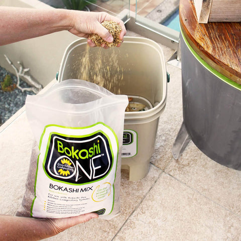 Person adding Bokashi Mix to a Bokashi One compost bucket.