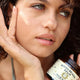 Woman applying a face balm to her cheek with a bottle of Bondi Beach Face Balm in the background.