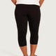 Black capri leggings shown from the back on a model, paired with a white top, against a light gray studio background.