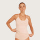 Boody Base Layer Cami Top Nude lifestyle shot of a woman with her hair up in the nude cami, hands at her hem, styled lifestyle photo