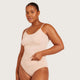 Boody Base Layer Cami Top Nude lifestyle shot of a woman in the nude cami and briefs with a hand at the hem, styled lifestyle photo