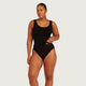 A woman modeling a black one-piece swimsuit against a light gray studio background. The brand name 'BOODY' is visible in small white text on the front left hip of the swimsuit.