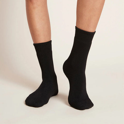 Black crew boot socks worn by a woman on a plain background