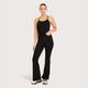 A woman modeling black flare pants, standing against a light gray studio background.