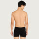 A man shown from the back wearing black boxer briefs, photographed against a plain light gray studio background.