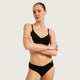 Boody Period & Leak Proof Classic Bikini Moderate-Heavy in black, full model shot of a woman with her hair tied up and arms folded