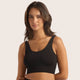 A woman wearing a black ribbed scoop-neck sports bra against a solid light beige background.