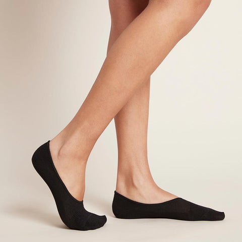Side view of black no-show socks worn by a model standing against a neutral background
