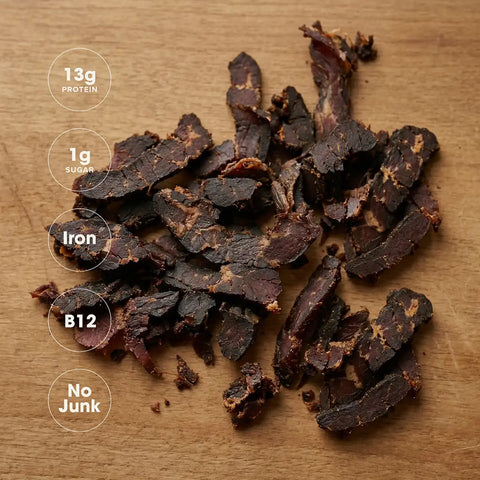 Dried beef jerky on a wooden surface with nutritional information displayed.