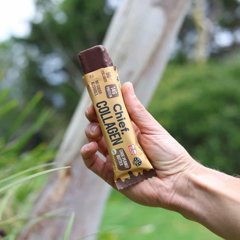 Hand holding a Chief Collagen bar with a natural background