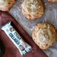 Cookies with a salted caramel topping on brown baking paper, next to a package of Chief Collagen salted caramel protein bar.