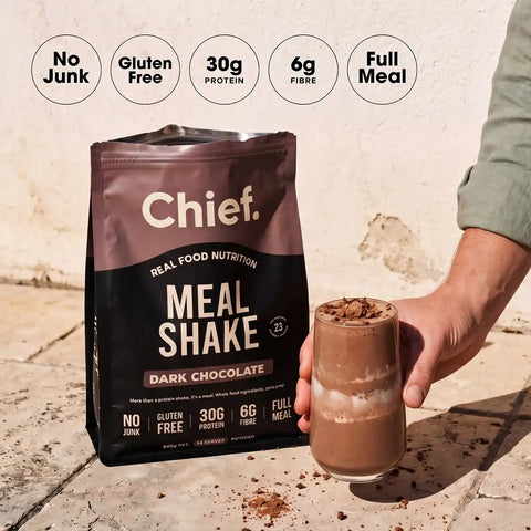 Chief Meal Shake package with a glass of dark chocolate shake on a tiled floor.