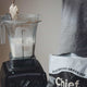 Blender with milk and whey powder being scooped into it for mixing into a smoothie.