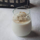 Glass of milk with a scoop of vanilla whey protein powder with a supplement whisk used for blending.