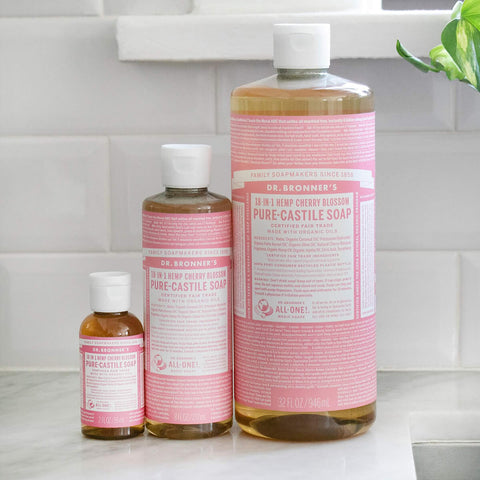 Three bottles of Dr. Bronner's Pure-Castile Soap on a kitchen counter.