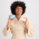 Woman holding a bar of soap and a bar of soap packaging against a plain background