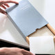 Person taking out a single sheet from box of dishwashing detergent sheets.
