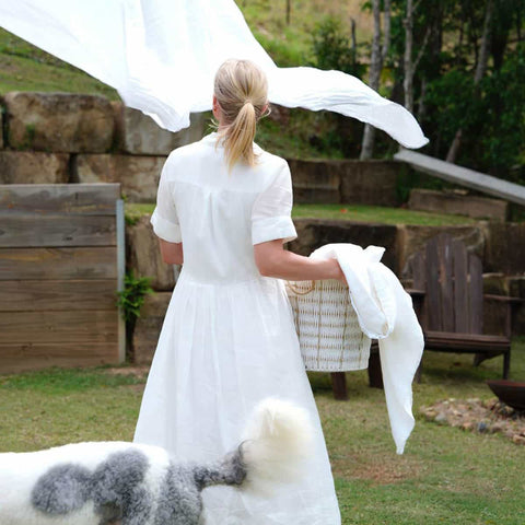 Woman in a white dress with a laundry basket, for bringing in clean sheets.