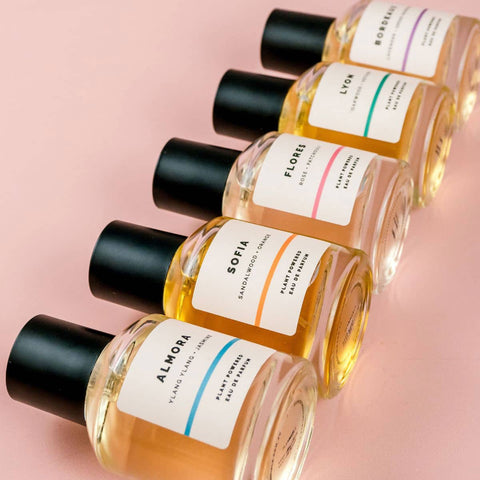 Row of ECO. Modern Essentials natural perfume bottles with labels on a pink background.