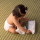 Baby sitting on a green mat with a package of wipes.