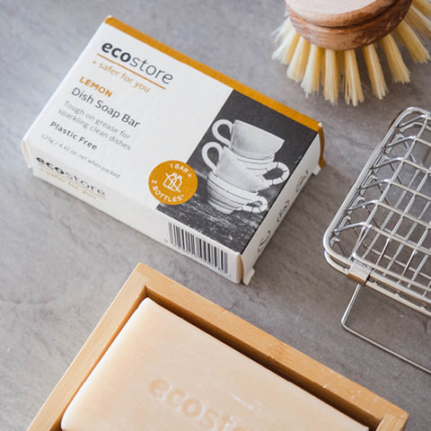 ecostore lemon dish soap bar with packaging and cleaning tools on a grey surface.