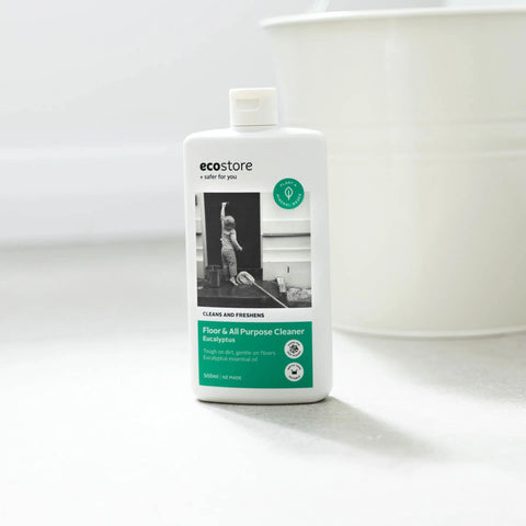 A 500ml bottle of ecostore Floor & All Purpose Cleaner stands on a light gray surface with a white bucket blurred in the background.