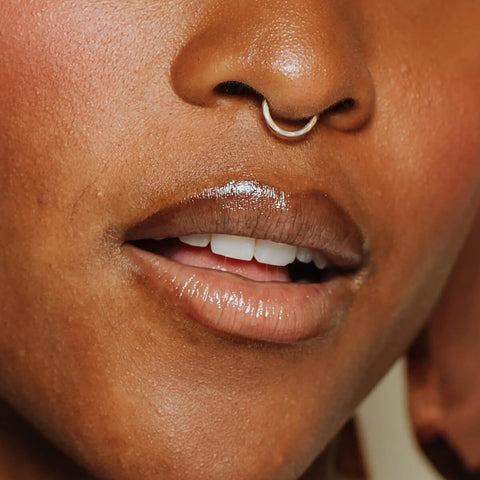 Model wearing Elate Beauty Better Balm in the shade 'Clarity', a clear lip conditioner that rehydrates and regenerates dry skin while protecting lips from environmental pollutants. It has a sheer shine and natural finish.