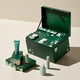 A green skincare gift set displayed open with multiple matching products arranged around it on a clean beige studio background. The set includes a large open box with star and wave graphics, a smaller matching box, a tube, and several small bottles in coordinated green tones.
